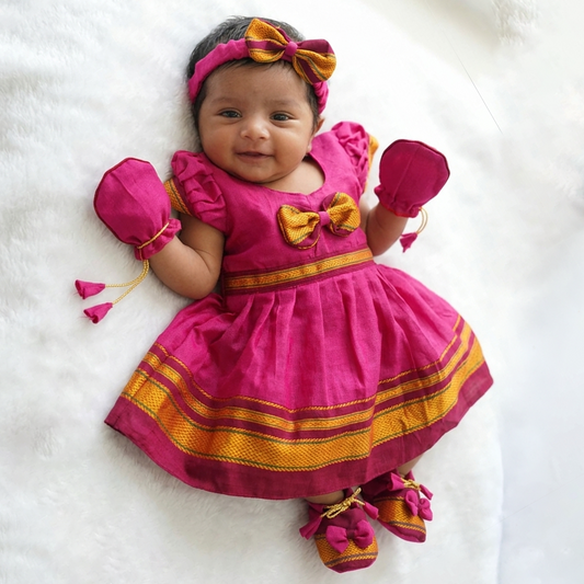 Baby girl wearing traditional pink Paithani dress with matching ethnic newborn accessories